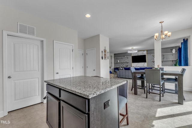 525 Willow Breeze Ct, Zebulon, NC 27597 - kitchen with light tile patterned floors, a chandelier, a kitchen island, light stone counters, and open floor plan