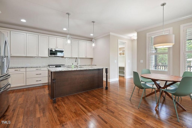 1962 Briar Chapel Pkwy, Chapel Hill, NC 27516 - kitchen with stainless steel appliances, ornamental molding, backsplash, white cabinetry, and a center island with sink