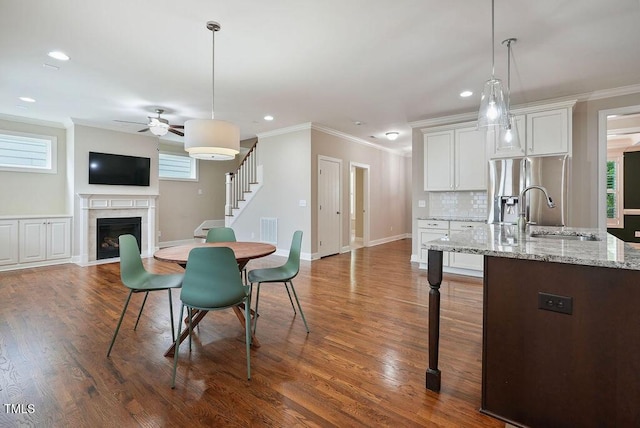 1962 Briar Chapel Pkwy, Chapel Hill, NC 27516 - dining area with a ceiling fan, stairway, a fireplace with flush hearth, ornamental molding, and dark wood finished floors