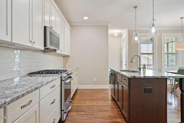 1962 Briar Chapel Pkwy, Chapel Hill, NC 27516 - kitchen featuring appliances with stainless steel finishes, backsplash, white cabinets, wood finished floors, and ornamental molding