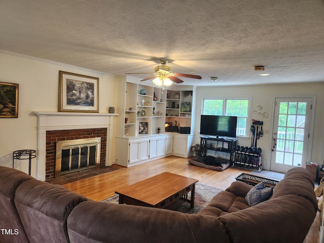 5760 Hesters Store Rd, Hurdle Mills, NC 27541 - living room with light wood finished floors, a ceiling fan, a brick fireplace, a textured ceiling, and ornamental molding