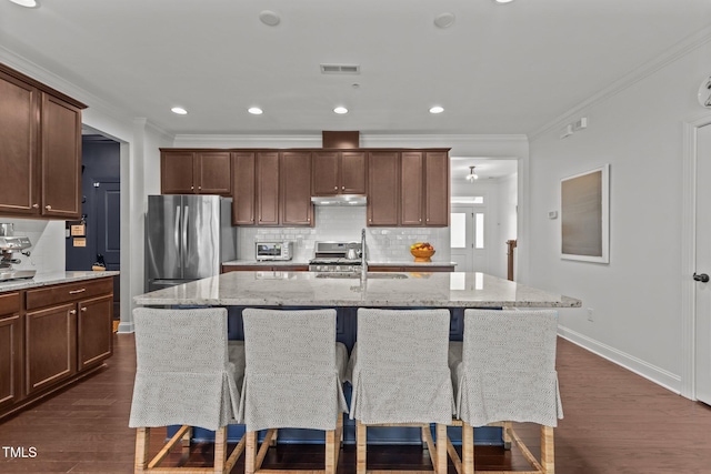 9302 Nellman Ln, Raleigh, NC 27617 - kitchen featuring stainless steel appliances, ornamental molding, backsplash, light stone counters, and a kitchen island with sink