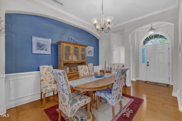 12227 Orchardgrass Ln, Raleigh, NC 27614 - dining space with a chandelier, arched walkways, wainscoting, wood finished floors, and ornamental molding