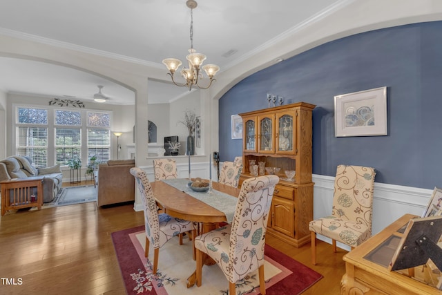 12227 Orchardgrass Ln, Raleigh, NC 27614 - dining space featuring arched walkways, a chandelier, ornamental molding, wood-type flooring, and wainscoting