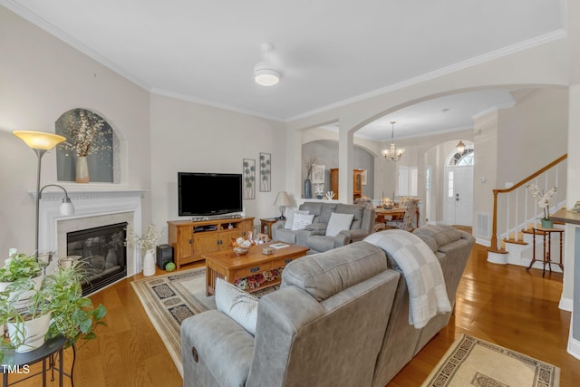 12227 Orchardgrass Ln, Raleigh, NC 27614 - living room featuring arched walkways, light wood-type flooring, stairway, crown molding, and a fireplace