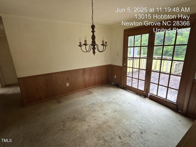 13015 Hobbton Hwy, Newton Grove, NC 28366 - unfurnished dining area with carpet flooring, a chandelier, wainscoting, wood walls, and ornamental molding