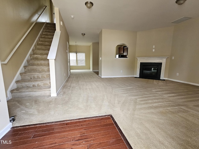 711 Keystone Park Dr Unit 78, Morrisville, NC 27560 - unfurnished living room featuring carpet floors, a fireplace with flush hearth, stairs, and a chandelier