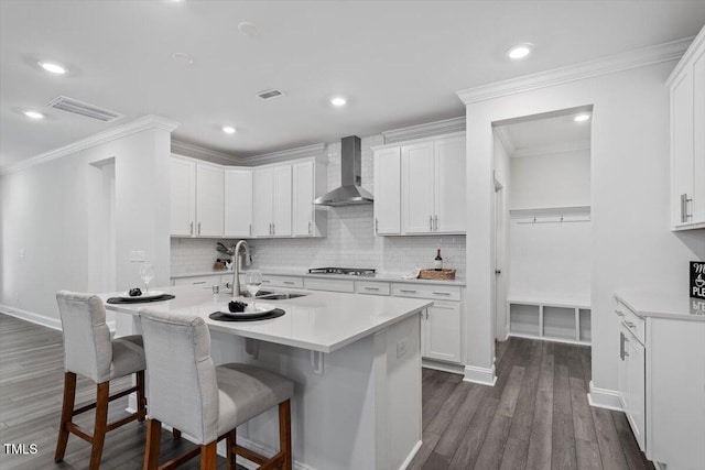 4940 Enlightenment Rd, Raleigh, NC 27616 - kitchen featuring wall chimney exhaust hood, stainless steel gas stovetop, a breakfast bar, backsplash, and crown molding
