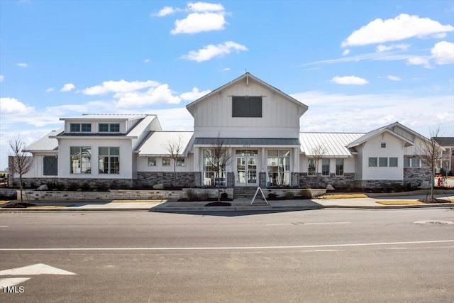 4940 Enlightenment Rd, Raleigh, NC 27616 - view of front of house featuring stone siding, french doors, a standing seam roof, a metal roof, and board and batten siding