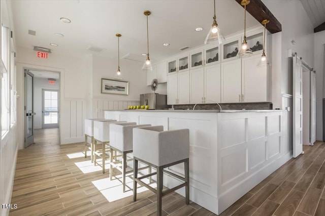 4940 Enlightenment Rd, Raleigh, NC 27616 - kitchen featuring freestanding refrigerator, wood finished floors, white cabinetry, glass insert cabinets, and a wainscoted wall