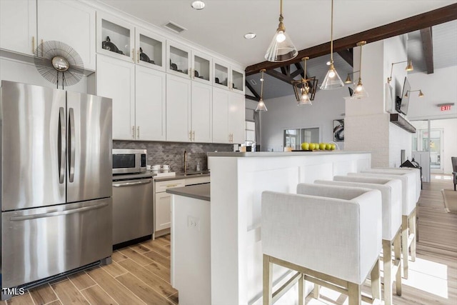 4940 Enlightenment Rd, Raleigh, NC 27616 - kitchen with stainless steel appliances, beam ceiling, backsplash, light wood-type flooring, and glass insert cabinets