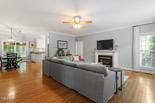 1819 Umstead Rd, Durham, NC 27712 - living room featuring a ceiling fan, light wood-style flooring, ornamental molding, and a glass covered fireplace