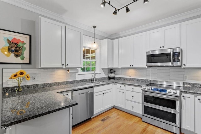 1819 Umstead Rd, Durham, NC 27712 - kitchen with appliances with stainless steel finishes, white cabinetry, dark stone countertops, hanging light fixtures, and ornamental molding