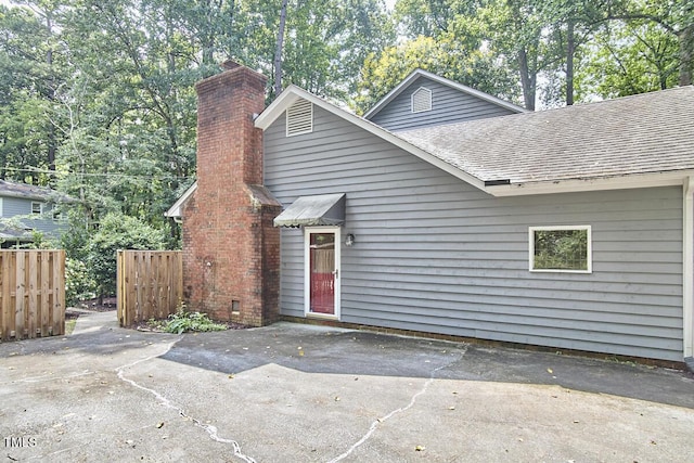 2334 Dawn Trl, Durham, NC 27712 - view of front of house featuring a shingled roof, a chimney, and a patio
