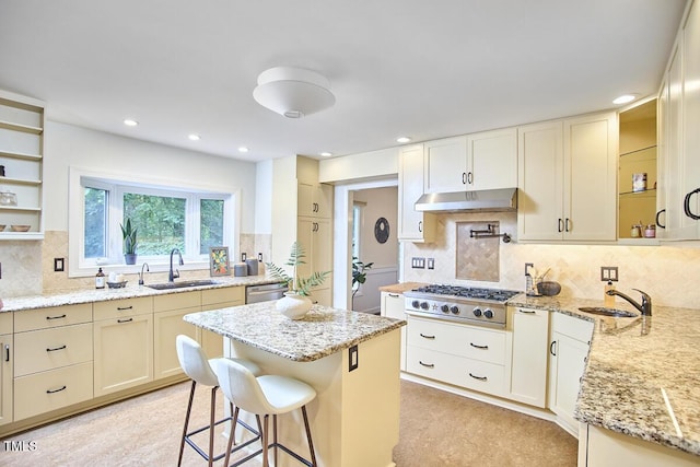 2334 Dawn Trl, Durham, NC 27712 - kitchen with appliances with stainless steel finishes, under cabinet range hood, light stone counters, tasteful backsplash, and a kitchen breakfast bar