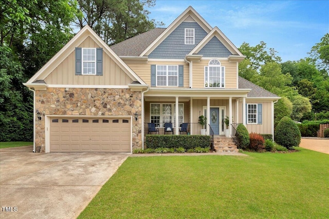 218 Kinvara Ct, Wake Forest, NC 27587 - craftsman-style house with driveway, covered porch, board and batten siding, a front lawn, and stone siding