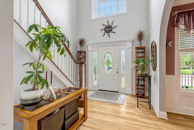 218 Kinvara Ct, Wake Forest, NC 27587 - foyer entrance featuring stairs, wood finished floors, a towering ceiling, arched walkways, and wainscoting