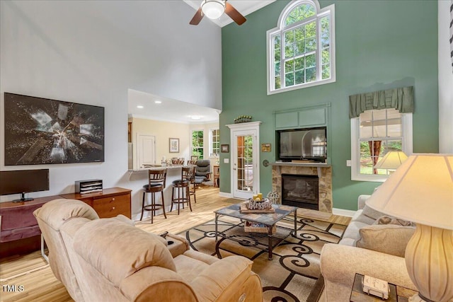 218 Kinvara Ct, Wake Forest, NC 27587 - living room featuring a towering ceiling, ceiling fan, wood finished floors, a glass covered fireplace, and crown molding