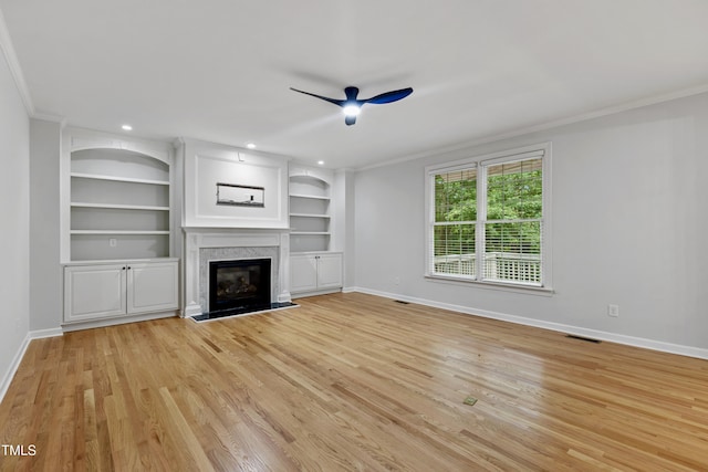 109 Aspenridge Dr, Holly Springs, NC 27540 - unfurnished living room featuring ceiling fan, ornamental molding, light wood finished floors, a high end fireplace, and built in features