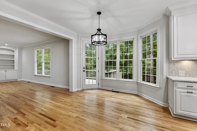 109 Aspenridge Dr, Holly Springs, NC 27540 - unfurnished dining area with crown molding, a chandelier, light wood-style floors, and built in shelves