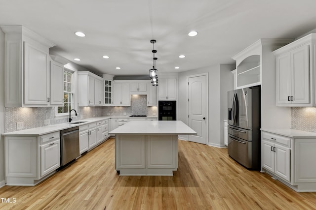 109 Aspenridge Dr, Holly Springs, NC 27540 - kitchen featuring appliances with stainless steel finishes, open shelves, a center island, light wood finished floors, and white cabinets