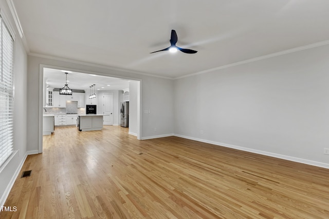 109 Aspenridge Dr, Holly Springs, NC 27540 - unfurnished living room with ceiling fan, light wood-type flooring, crown molding, and a chandelier