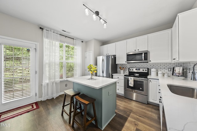 4413 Sugarbend Way, Raleigh, NC 27606 - kitchen with stainless steel appliances, a center island, backsplash, white cabinets, and a kitchen bar