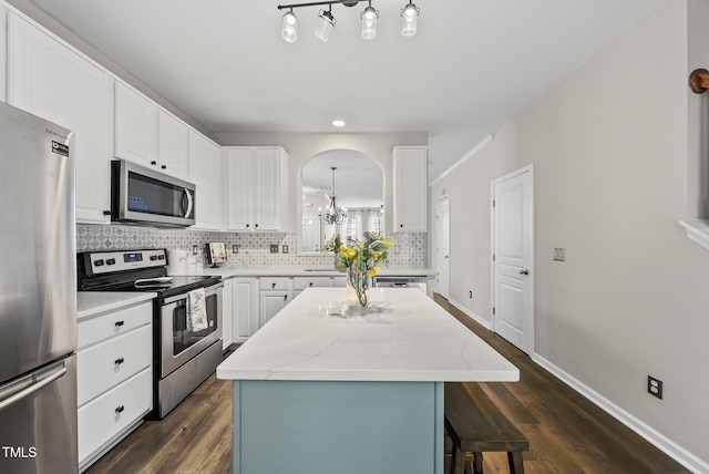 4413 Sugarbend Way, Raleigh, NC 27606 - kitchen featuring appliances with stainless steel finishes, a center island, a chandelier, decorative backsplash, and dark wood finished floors