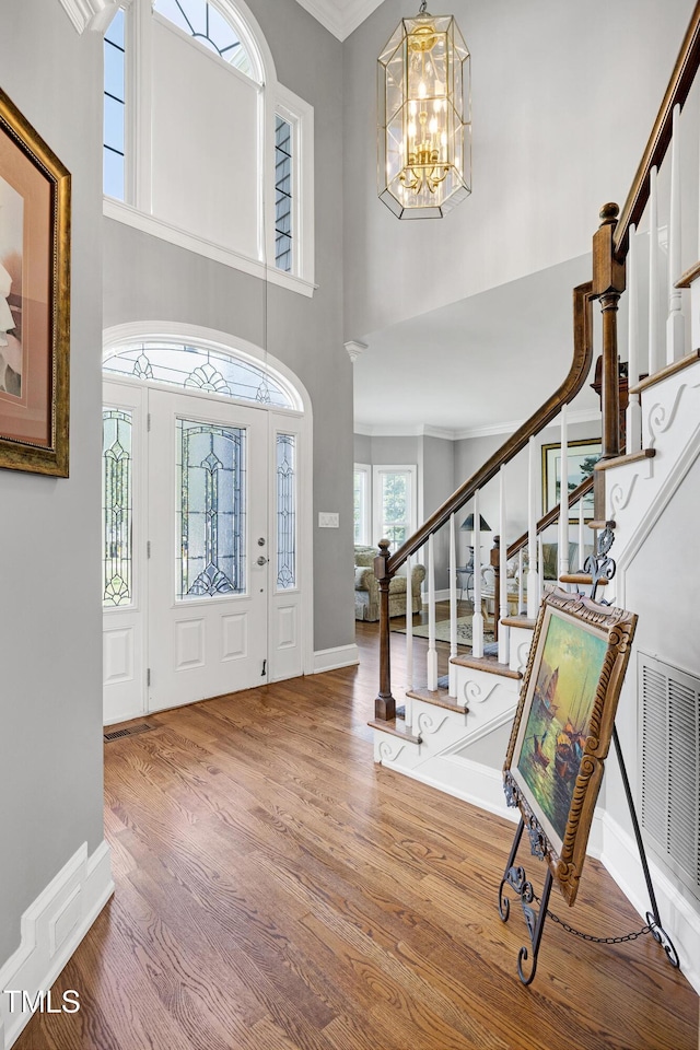 5013 Wheatridge Dr, Fuquay Varina, NC 27526 - entryway featuring wood finished floors, a chandelier, a high ceiling, stairs, and ornamental molding