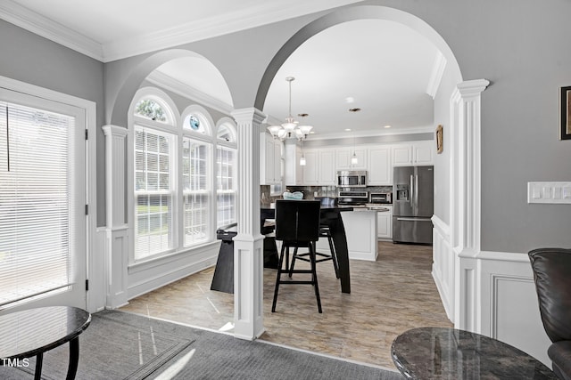 5013 Wheatridge Dr, Fuquay Varina, NC 27526 - dining room featuring ornate columns, arched walkways, a decorative wall, healthy amount of natural light, and ornamental molding
