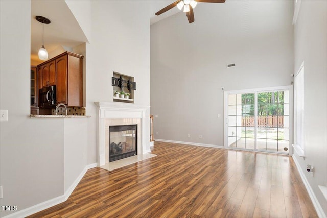 1016 Goldmist Ln, Durham, NC 27713 - unfurnished living room with ceiling fan, wood finished floors, a high ceiling, and a tiled fireplace
