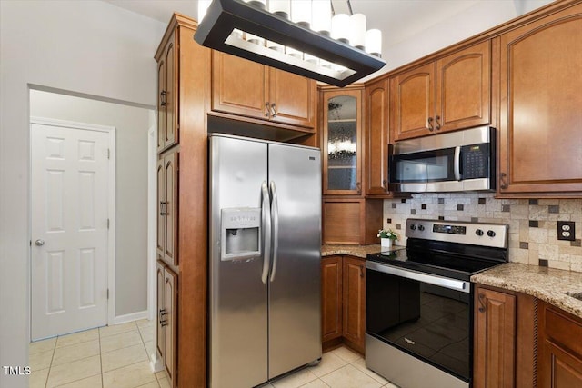 1016 Goldmist Ln, Durham, NC 27713 - kitchen featuring stainless steel appliances, light tile patterned flooring, brown cabinets, and backsplash