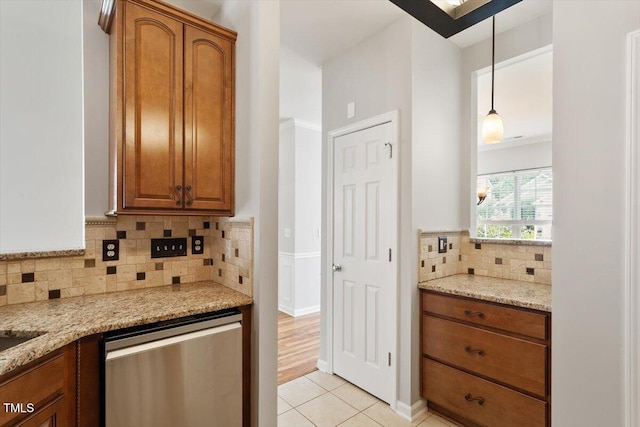 1016 Goldmist Ln, Durham, NC 27713 - kitchen featuring dishwasher, brown cabinets, light tile patterned flooring, light stone countertops, and tasteful backsplash