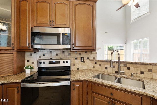 1016 Goldmist Ln, Durham, NC 27713 - kitchen featuring stainless steel appliances, decorative backsplash, light stone countertops, glass insert cabinets, and a high ceiling