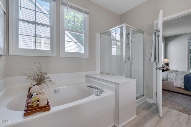 5308 Bentgrass Dr, Raleigh, NC 27610 - bathroom featuring wood finished floors, a bath, a stall shower, and ensuite bathroom