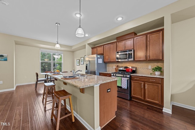 4124 Sykes St, Cary, NC 27519 - kitchen featuring stainless steel appliances, dark wood-type flooring, a center island with sink, and brown cabinetry