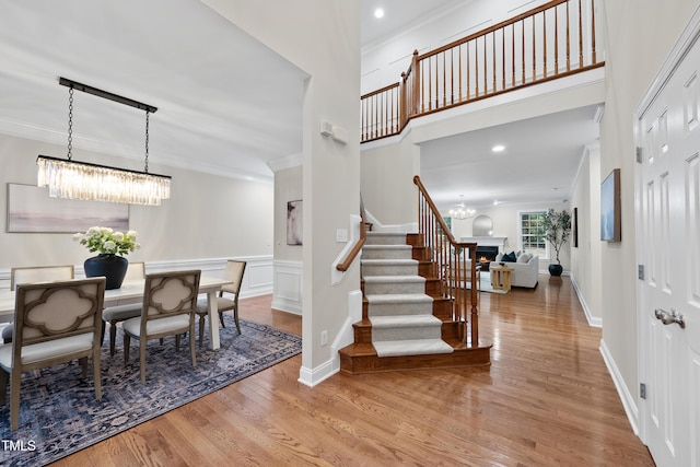 501 Ivyshaw Rd, Cary, NC 27519 - foyer entrance with a chandelier, crown molding, wood finished floors, stairs, and a warm lit fireplace