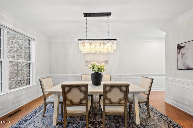 501 Ivyshaw Rd, Cary, NC 27519 - dining room with wood finished floors, ornamental molding, a chandelier, a wainscoted wall, and a decorative wall