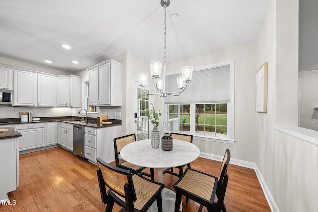 501 Ivyshaw Rd, Cary, NC 27519 - kitchen featuring appliances with stainless steel finishes, a chandelier, dark countertops, light wood finished floors, and backsplash