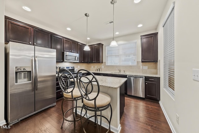7235 Terregles Dr, Raleigh, NC 27617 - kitchen with stainless steel appliances, dark brown cabinetry, a kitchen breakfast bar, dark wood-style flooring, and recessed lighting