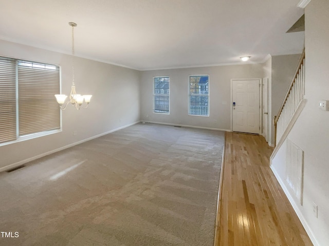 6701 Winding Arch Dr, Durham, NC 27713 - unfurnished living room with a chandelier, light wood-style flooring, stairs, and ornamental molding