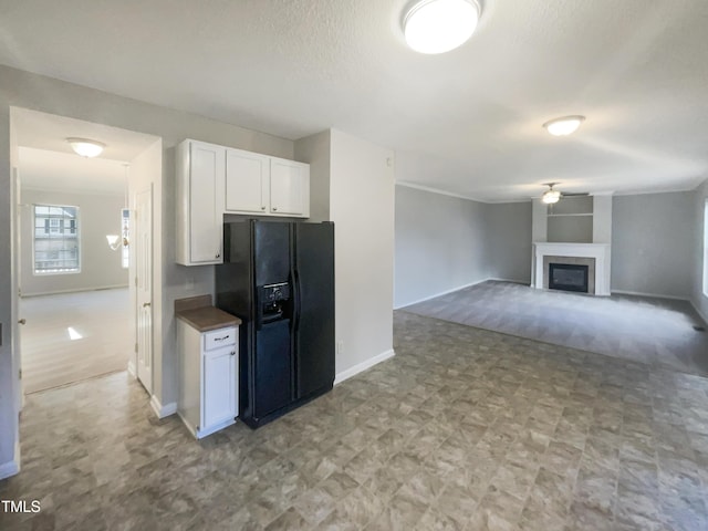 6701 Winding Arch Dr, Durham, NC 27713 - kitchen featuring black fridge, white cabinetry, a fireplace, and light flooring