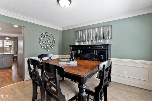 2302 Fordcrest Dr, Apex, NC 27502 - dining space with crown molding, light wood-style floors, wainscoting, and a textured ceiling