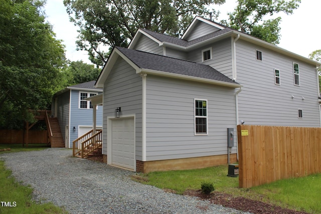4511 Denfield St, Durham, NC 27704 - view of side of property featuring roof with shingles, gravel driveway, an attached garage, and stairway