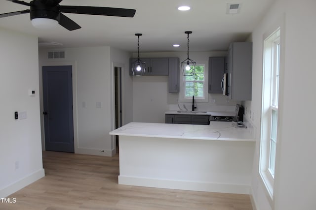 4511 Denfield St, Durham, NC 27704 - kitchen with gray cabinetry, stove, a peninsula, light stone countertops, and recessed lighting