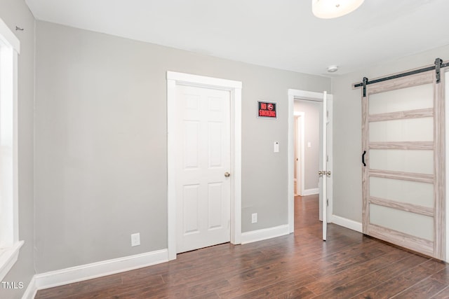 1401 Robinhood Rd, Durham, NC 27701 - unfurnished bedroom featuring a barn door and dark wood finished floors