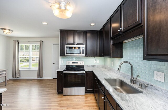 281 Kinsman Ct, Fuquay Varina, NC 27526 - kitchen featuring stainless steel appliances, backsplash, light wood finished floors, light stone counters, and dark brown cabinets