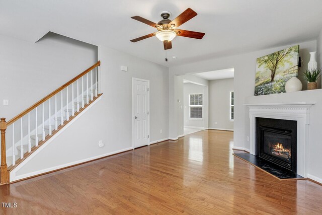 160 Chandler Springs Dr, Holly Springs, NC 27540 - unfurnished living room with stairway, wood finished floors, a ceiling fan, and a glass covered fireplace