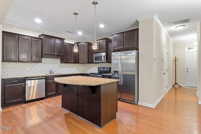 1213 Silver Beach Way, Raleigh, NC 27606 - kitchen with stainless steel appliances, dark brown cabinets, ornamental molding, light wood finished floors, and a kitchen island