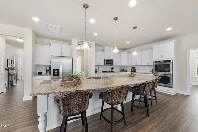 433 Village Bend Dr, Fuquay Varina, NC 27526 - kitchen with appliances with stainless steel finishes, white cabinetry, dark wood-type flooring, a spacious island, and recessed lighting